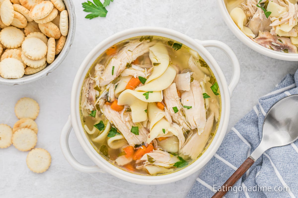 Close up image of chicken noodle soup in a white bowl