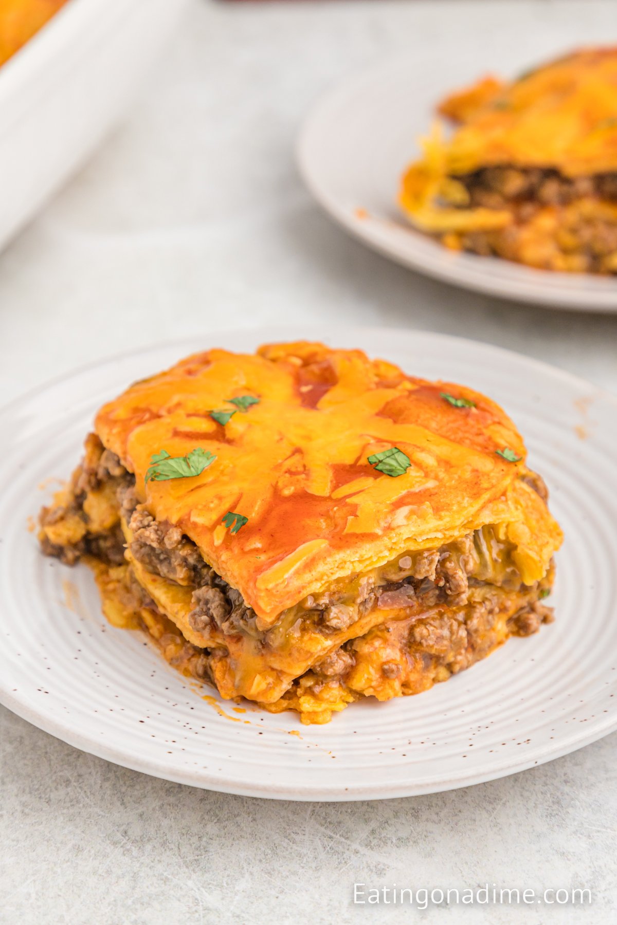 A close up image of a serving of beef enchilada casserole on a white plate