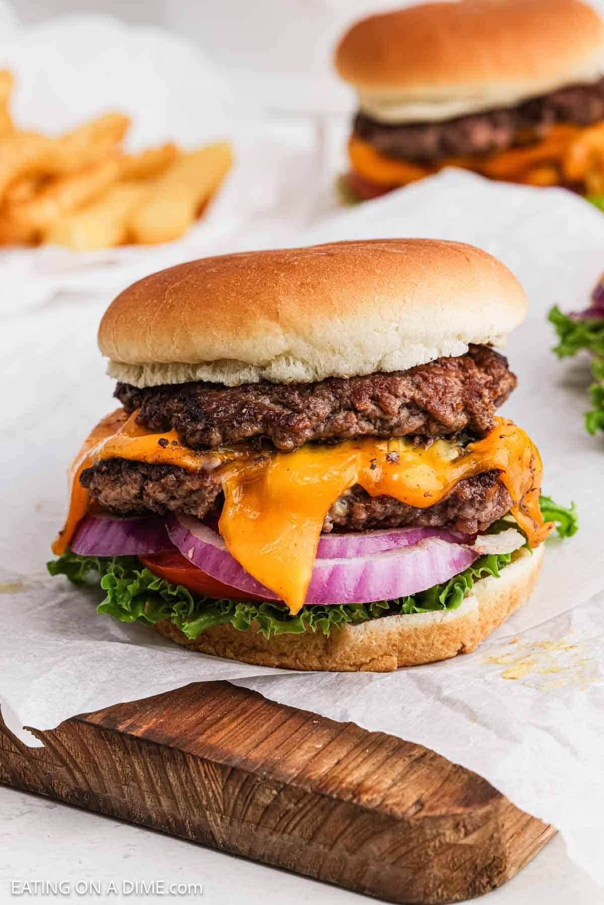 Close up image of cheeseburgers topped with red onions and lettuce.