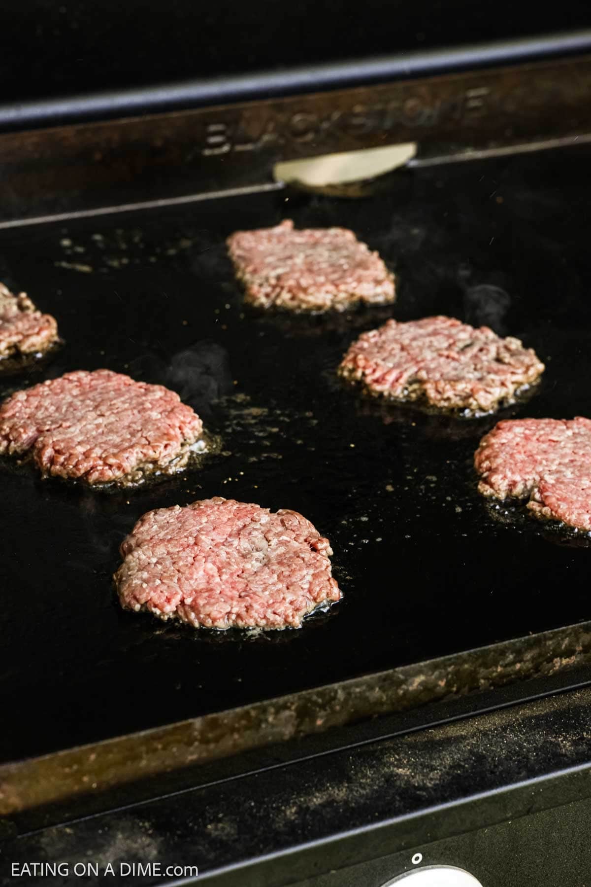 Hamburger patties on the flat top griddle.