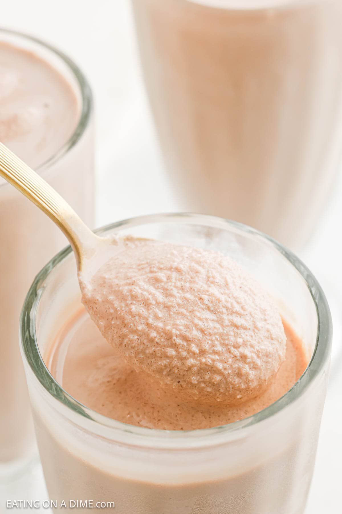 A serving of the chocolate frosty on a spoon over a the frosty in a clear glass
