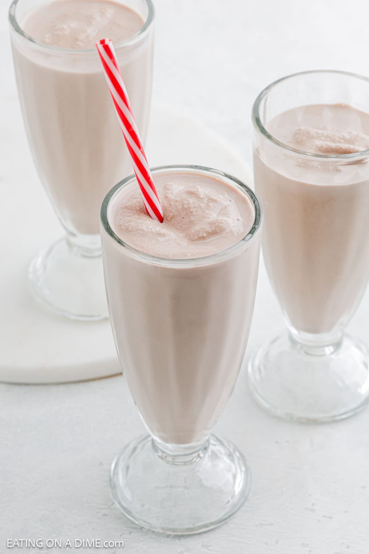 Frosty Milkshake in a tall clear glass with a red and white straw