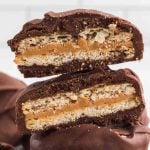 A close-up of two Chocolate Covered Ritz Crackers stacked, each revealing a tempting layer of caramel and crispy wafer inside, set against a light background.