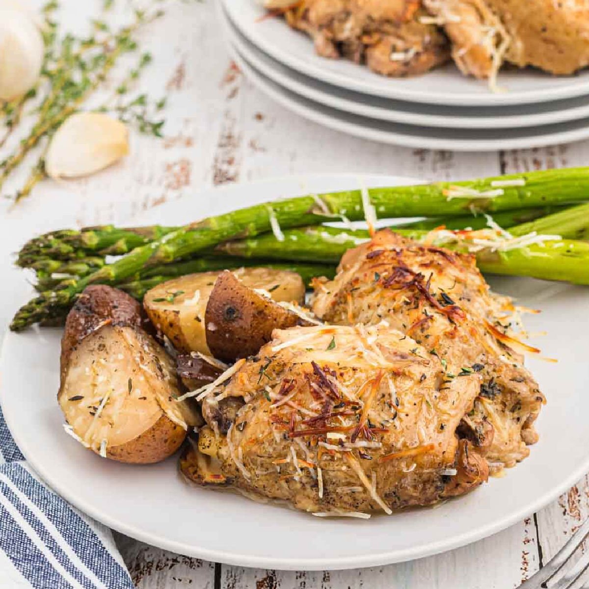 Chicken thighs, asparagus, potatoes on a white plate
