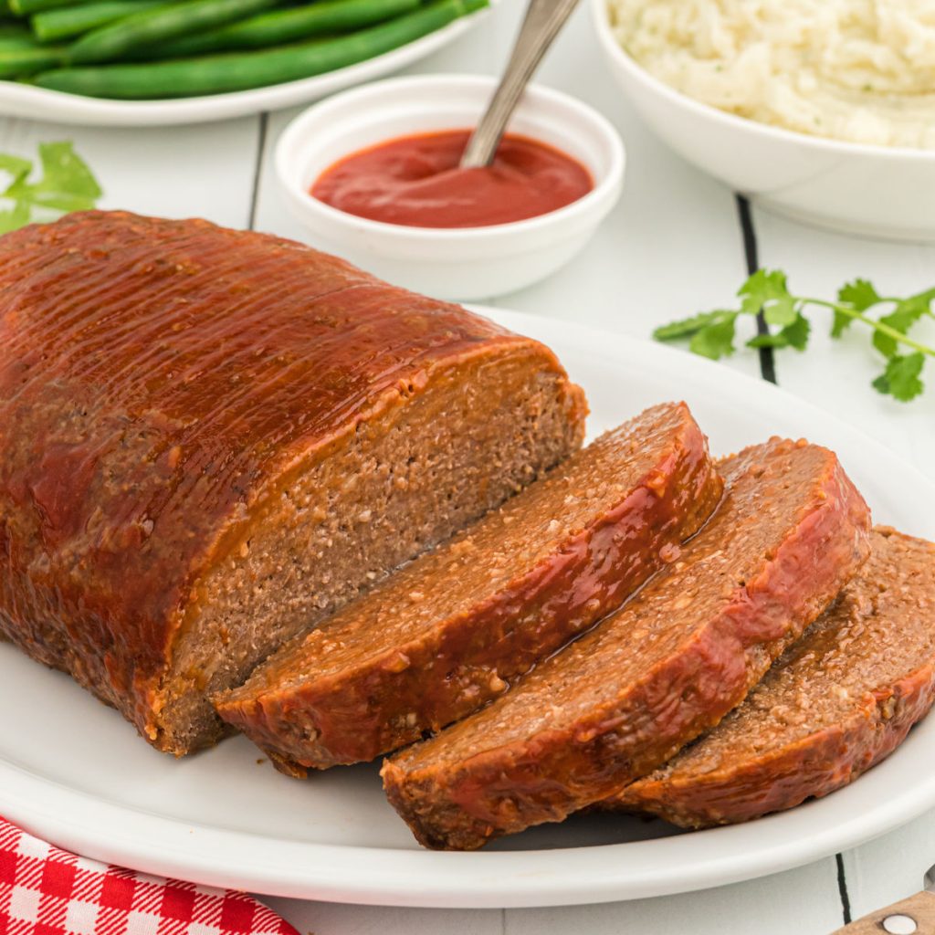 Meatloaf sliced on a white plate with a side of ketchup