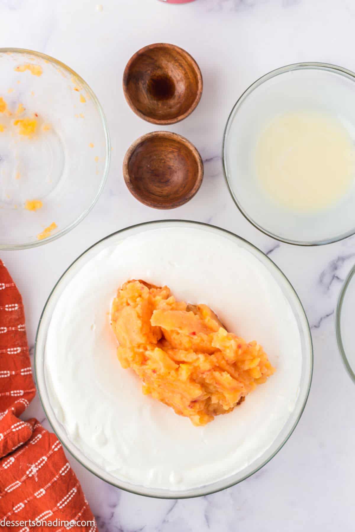 Peach puree added to the whipping cream mixture in a bowl.