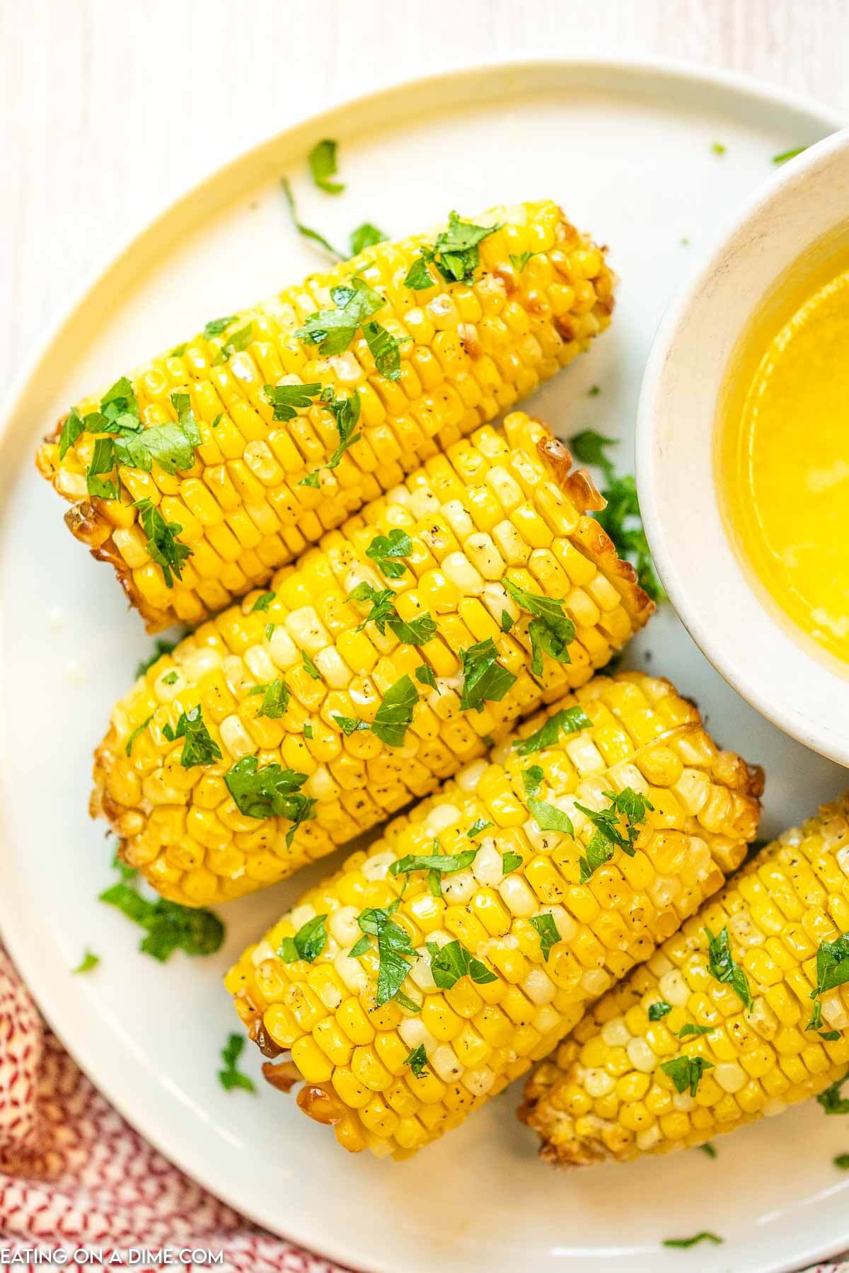 Air Fryer Corn on the Cob on a plate topped with cilantro with a side of butter