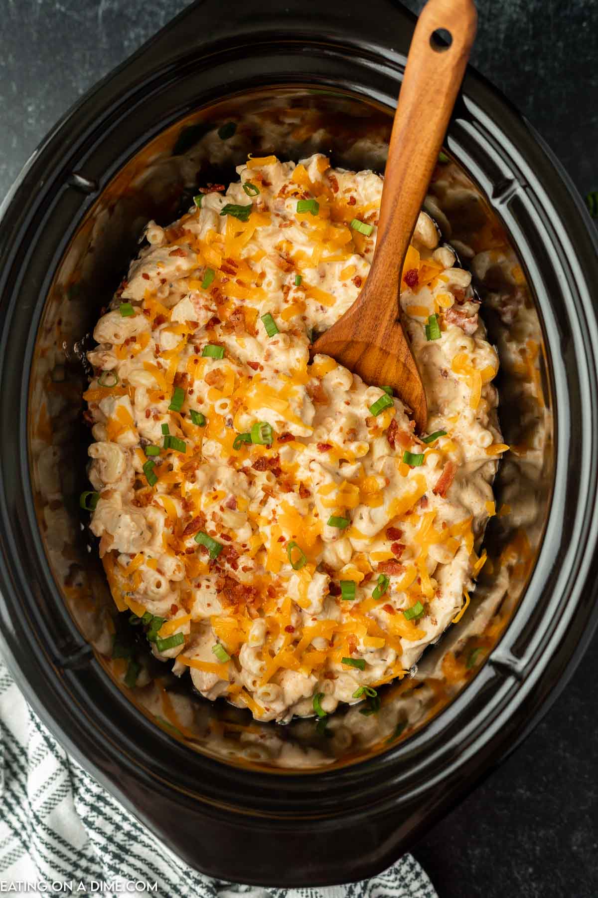 Crack chicken casserole in a crock pot with a wooden spoon