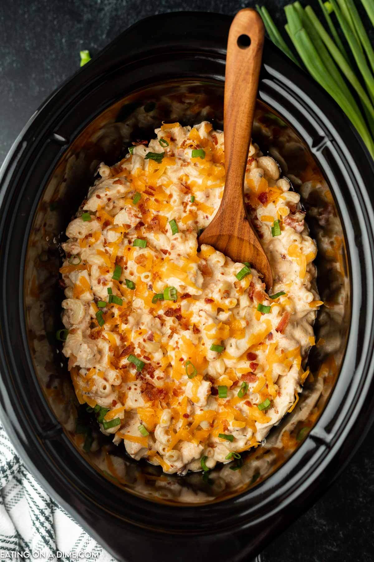 Crack chicken casserole in a crock pot with a wooden spoon