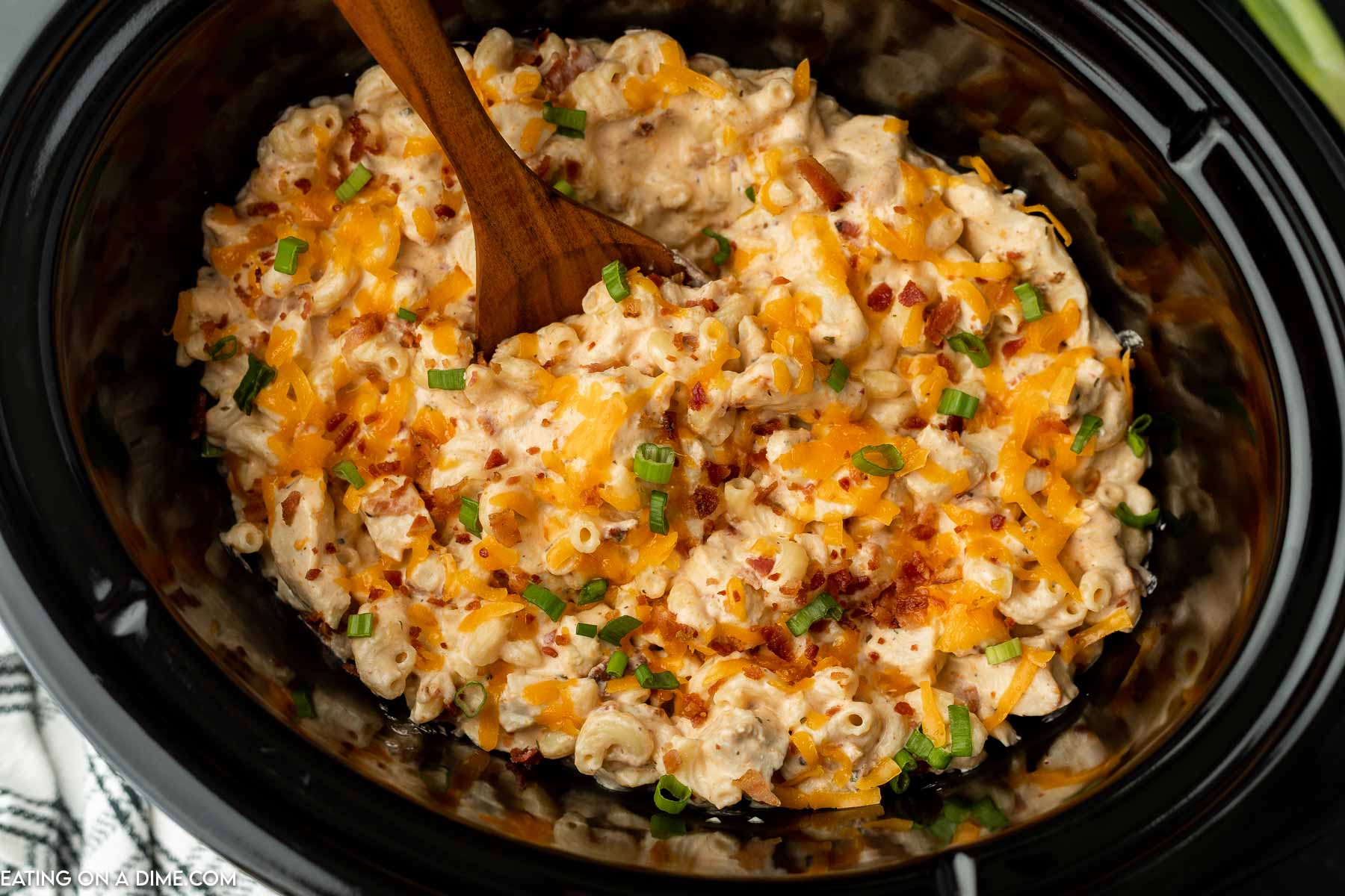 Crack chicken casserole in a crock pot with a wooden spoon