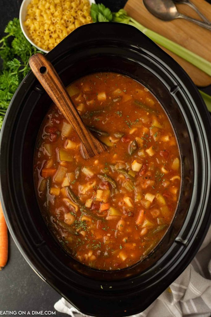 Minestrone Soup in the crock pot with a wooden spoon
