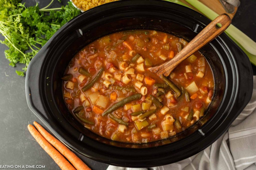 Minestrone Soup in the crock pot with a wooden spoon