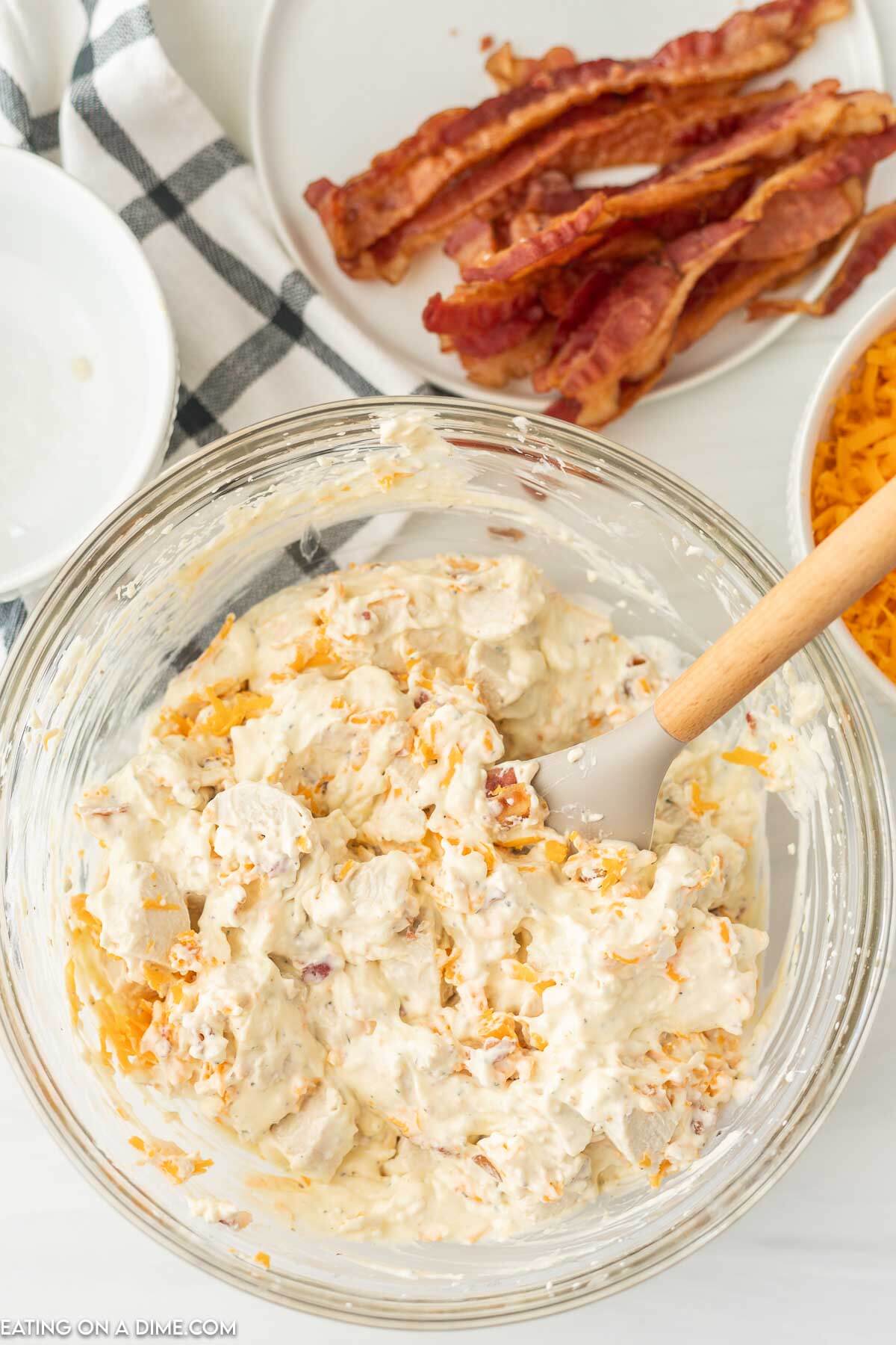 Mixing the crack chicken mixture in a bowl with a spoon