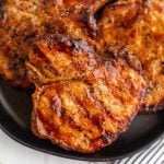 BBQ grilled pork chops stacked on a plate.