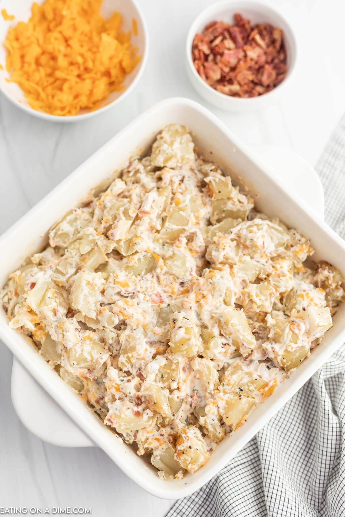 Sour cream, ranch, bacon and cheese are mixed with the baked potatoes pieces and placed back in the baking dish