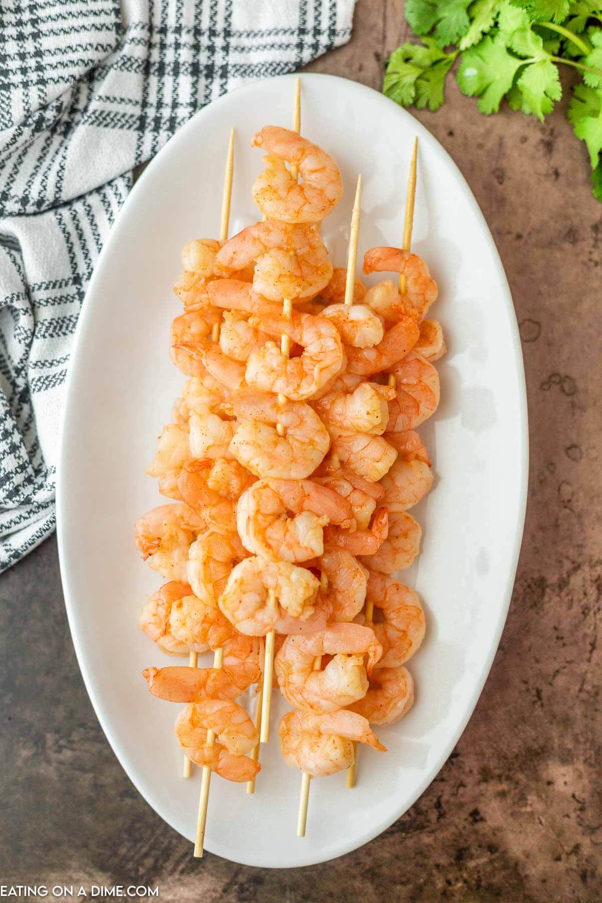 Shrimp on skewers stacked on a white platter