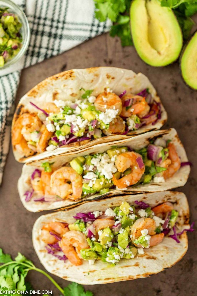 Shrimp tacos topped with red cabbage and diced avocado