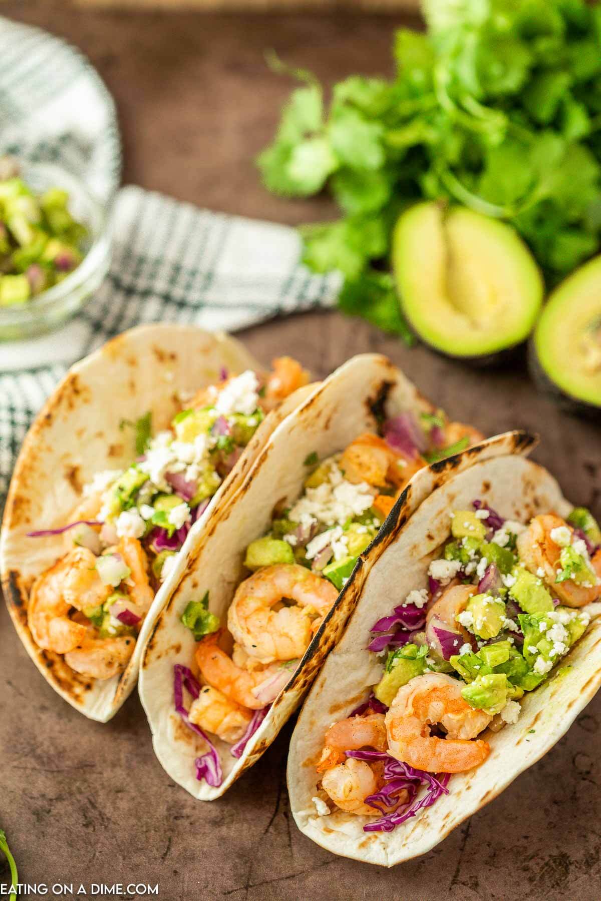 Shrimp tacos topped with red cabbage and diced avocado