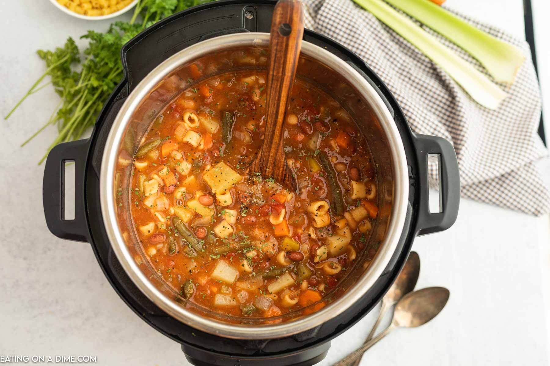 Minestrone soup in the instant pot with a wooden spoon