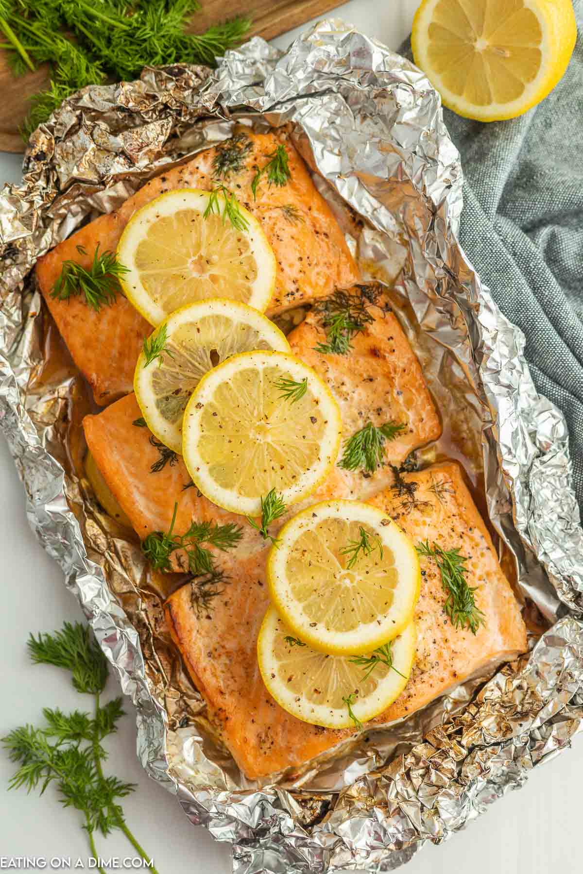 grilled salmon in foil topped with lemon and fresh herbs