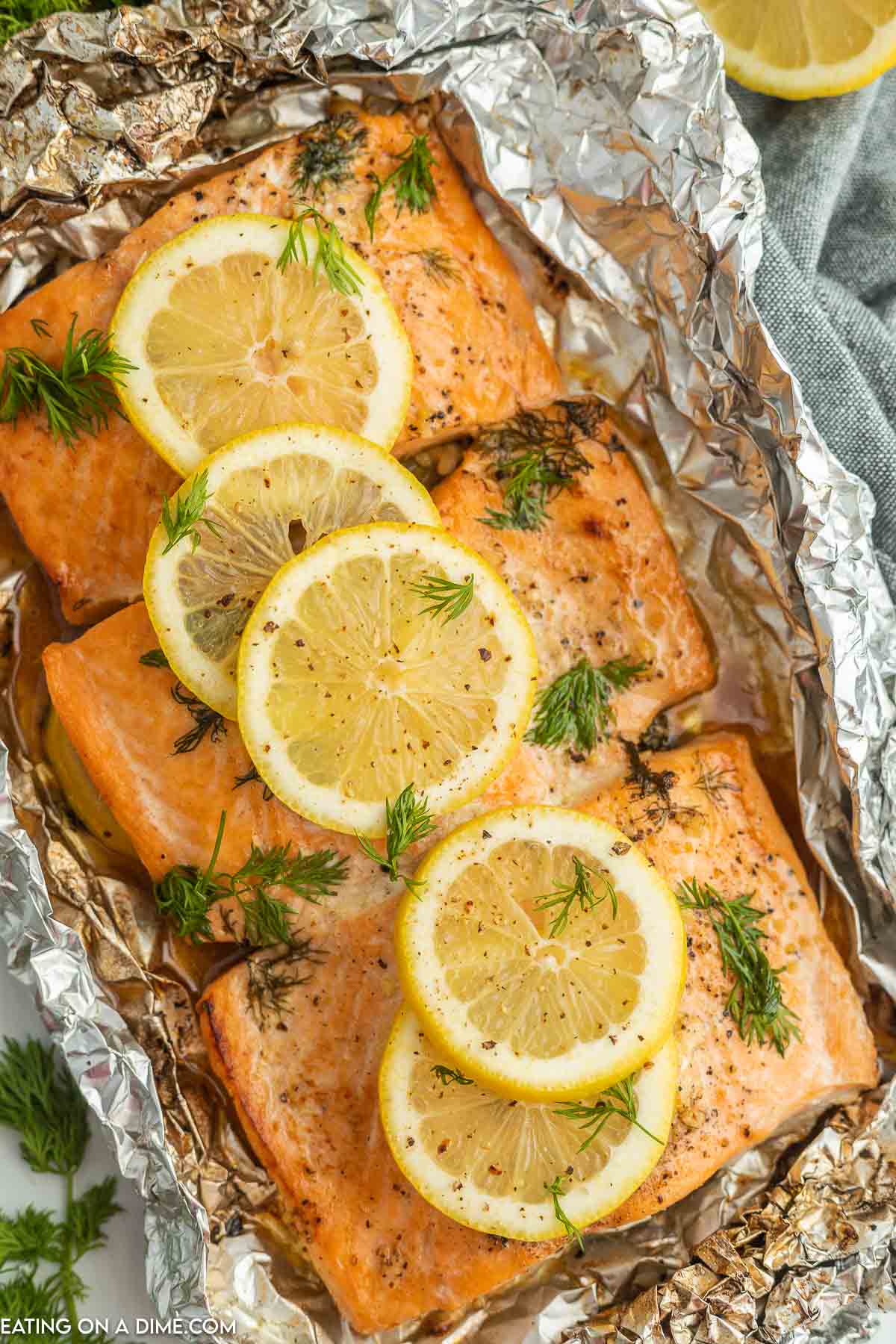 grilled salmon in foil topped with lemon slices and fresh dill