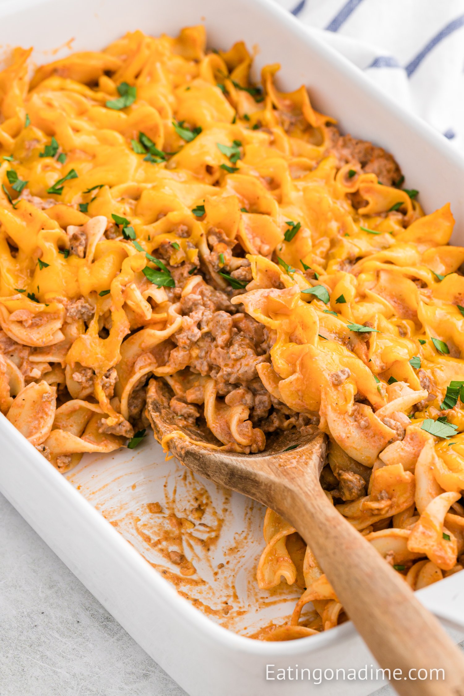 Hamburger casserole in a baking dish with a wooden spoon