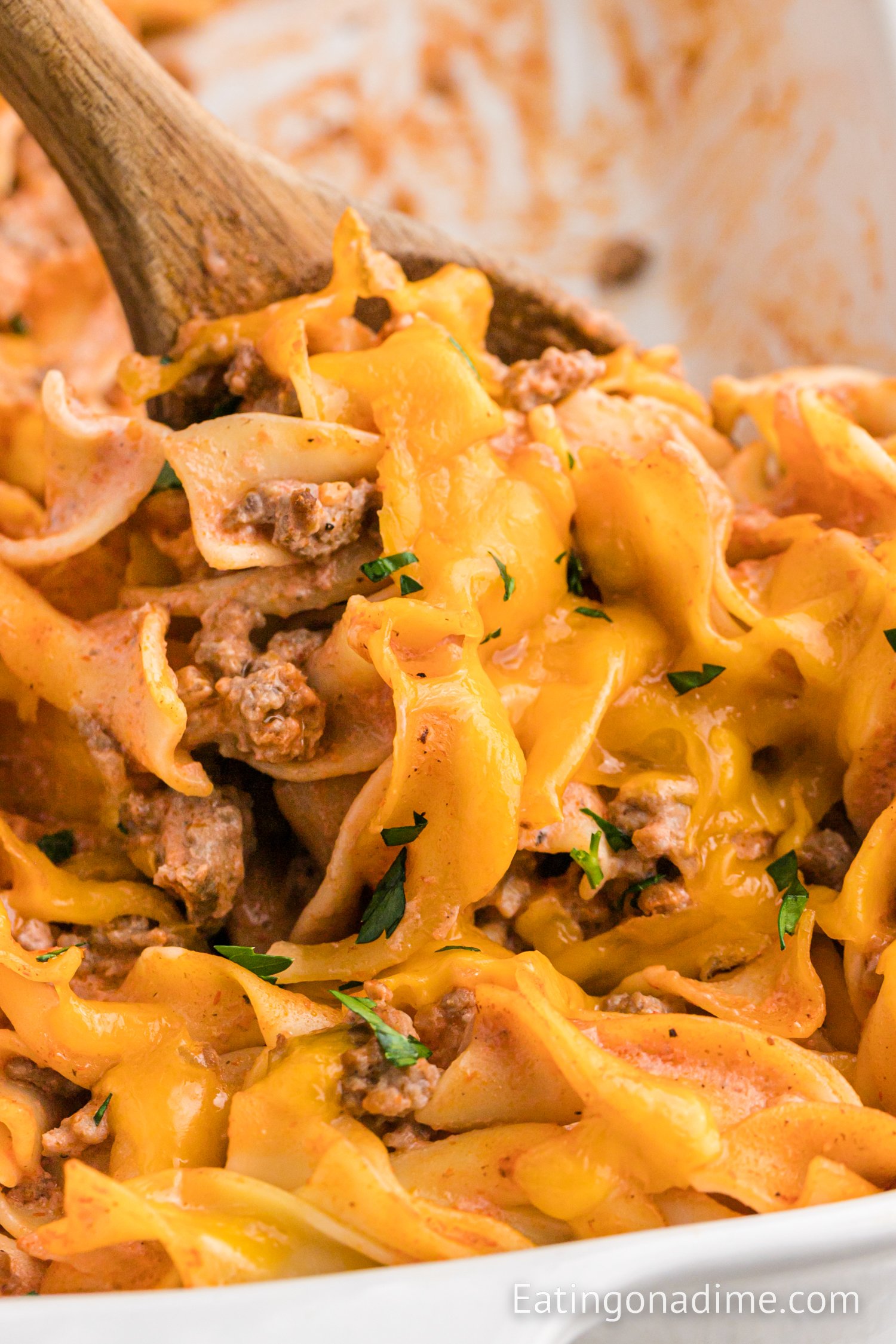 Hamburger casserole in a baking dish with a wooden spoon