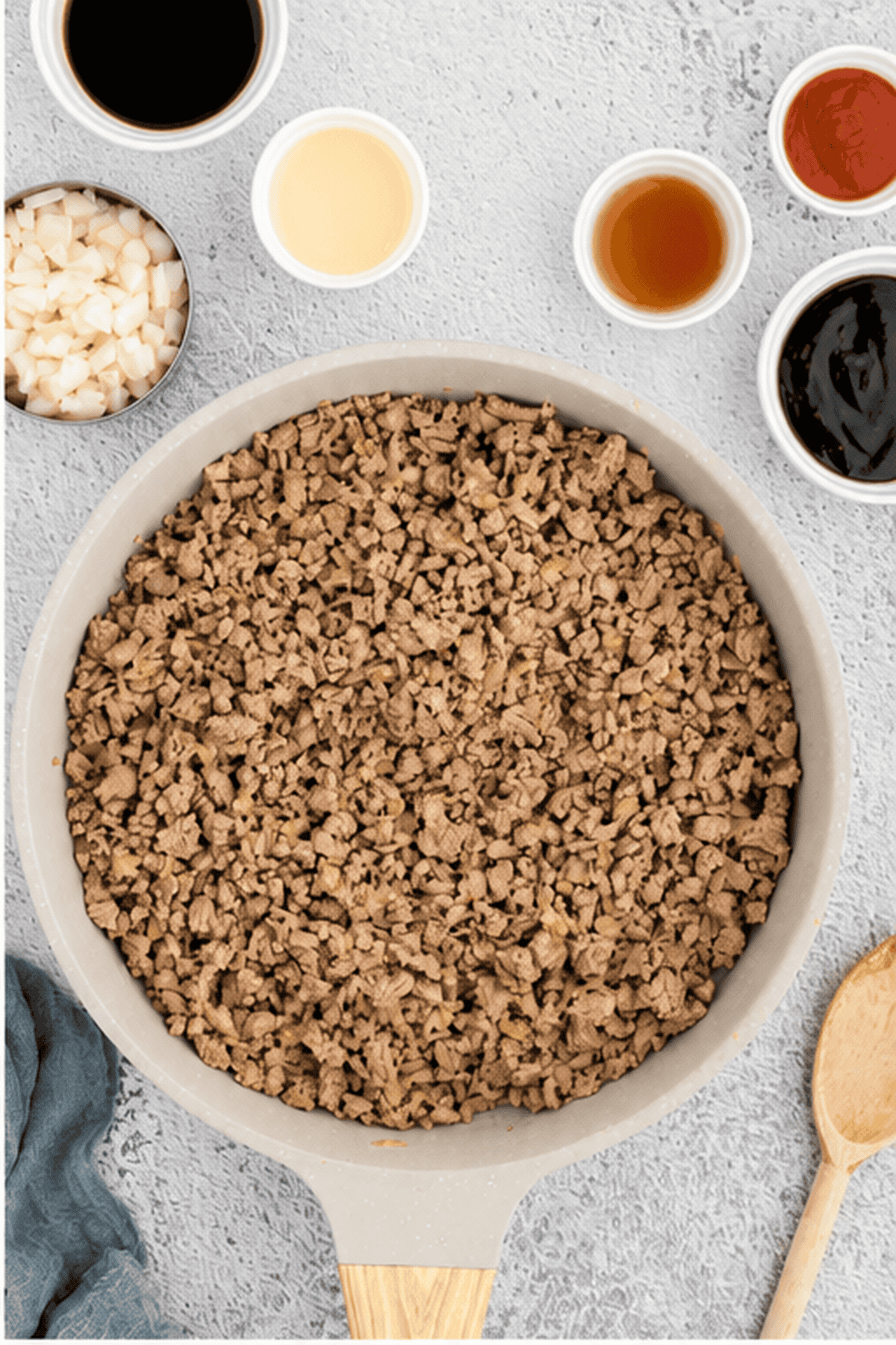 Cooked ground chicken is added to the skillet with small bowls of sauces on the side.