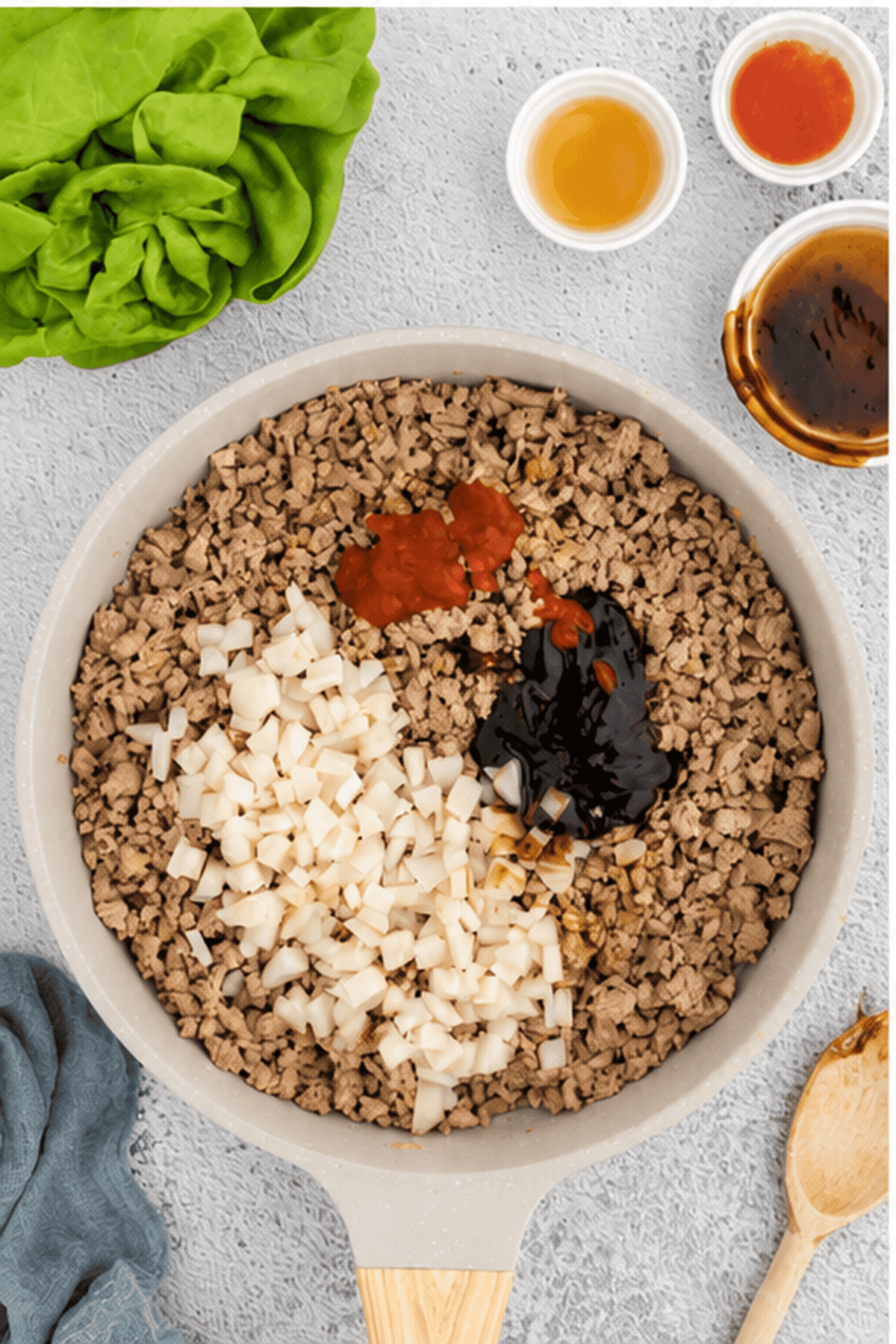 Diced onions, soy sauce, hoisin sauce and vinegar added to the top of the ground chicken in the skillet.