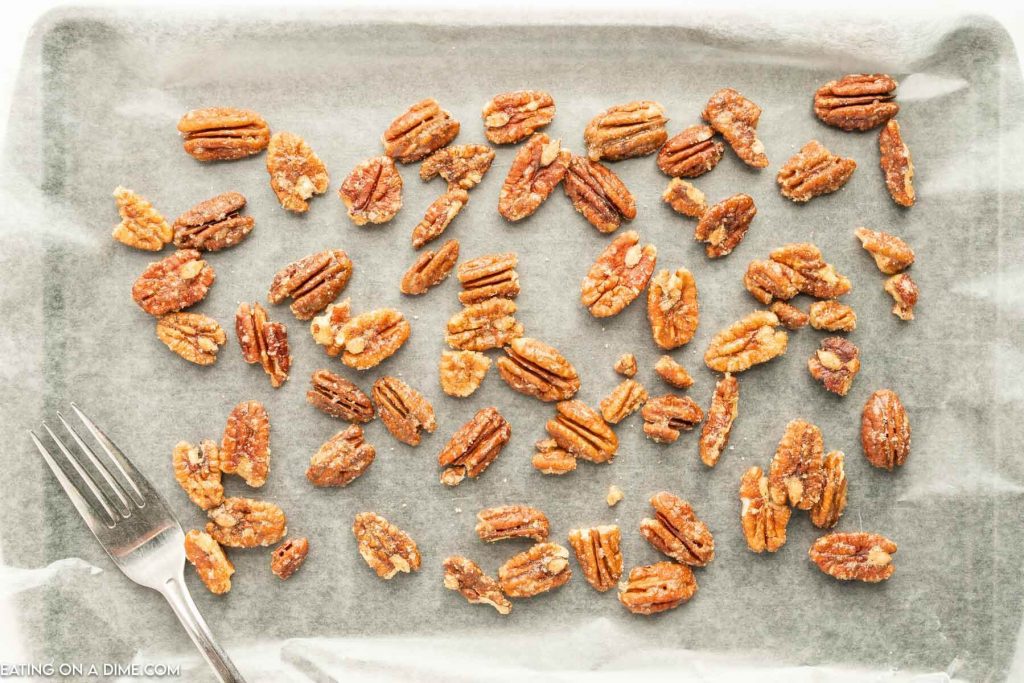 candied pecans on a lined baking sheet with a fork