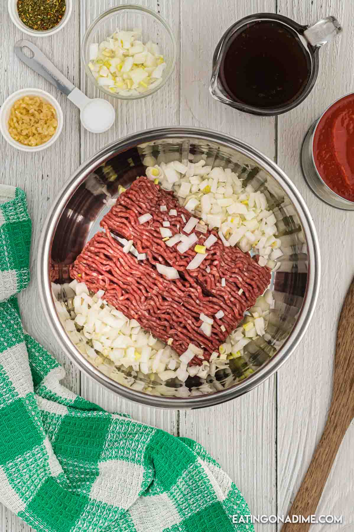 Ground beef with chopped onions in the instant pot with small bowl of minced onions, Italian seasoning and beef broth