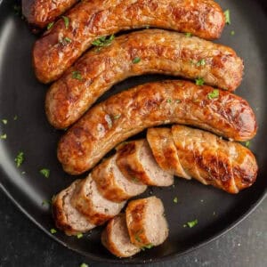 Cooked air fryer brats placed on a black plate.