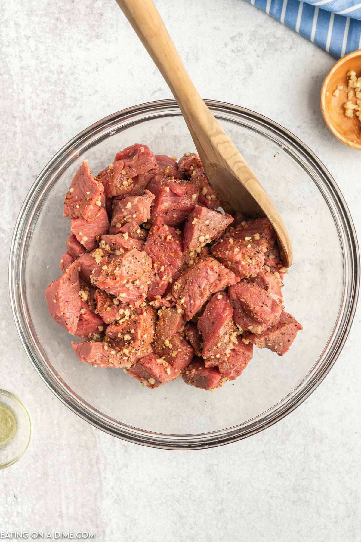 Mixing the steak bites in a bowl with the marinade