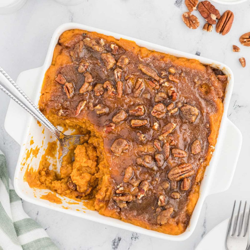 sweet potato casserole in a baking dish with a serving on a spoon