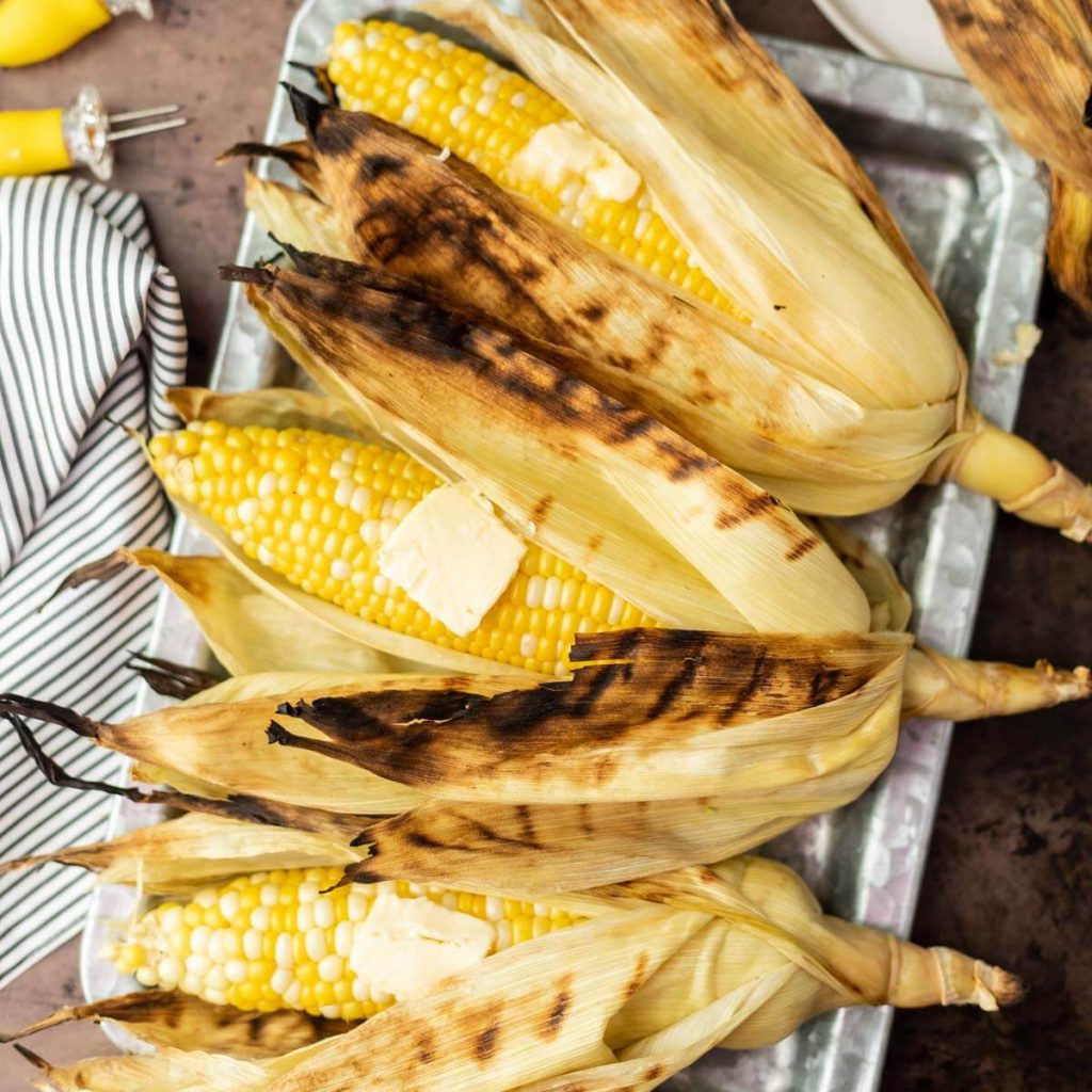 Grilled Corn in the Husk on a tray.
