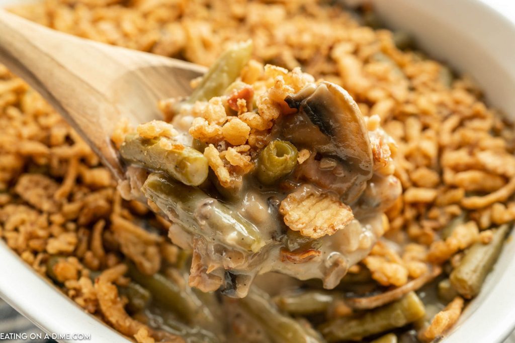 Green Bean Casserole with Bacon in baking dish with a serving on a wooden spoon