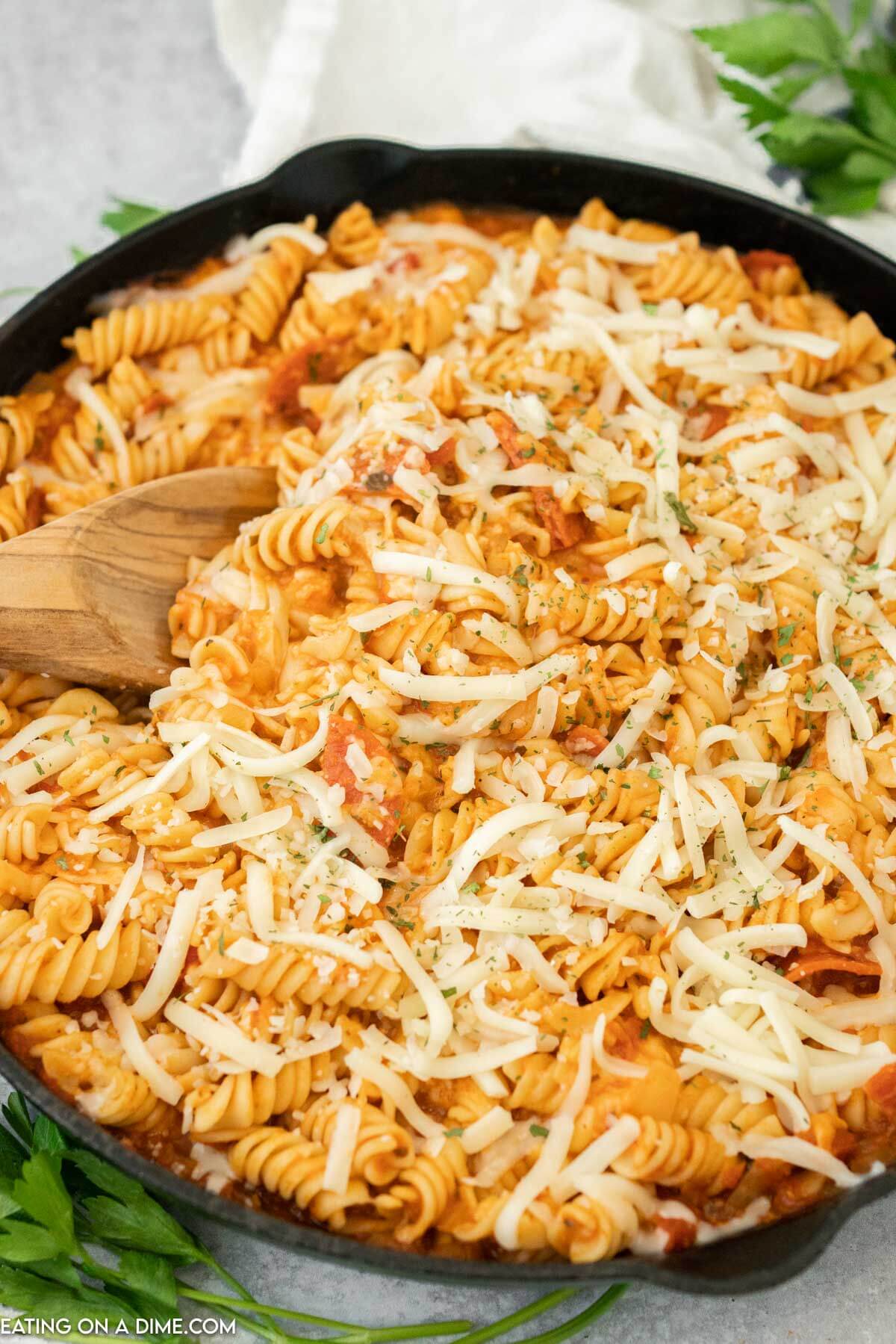 Pepperoni pasta being stirred with a wooden spoon