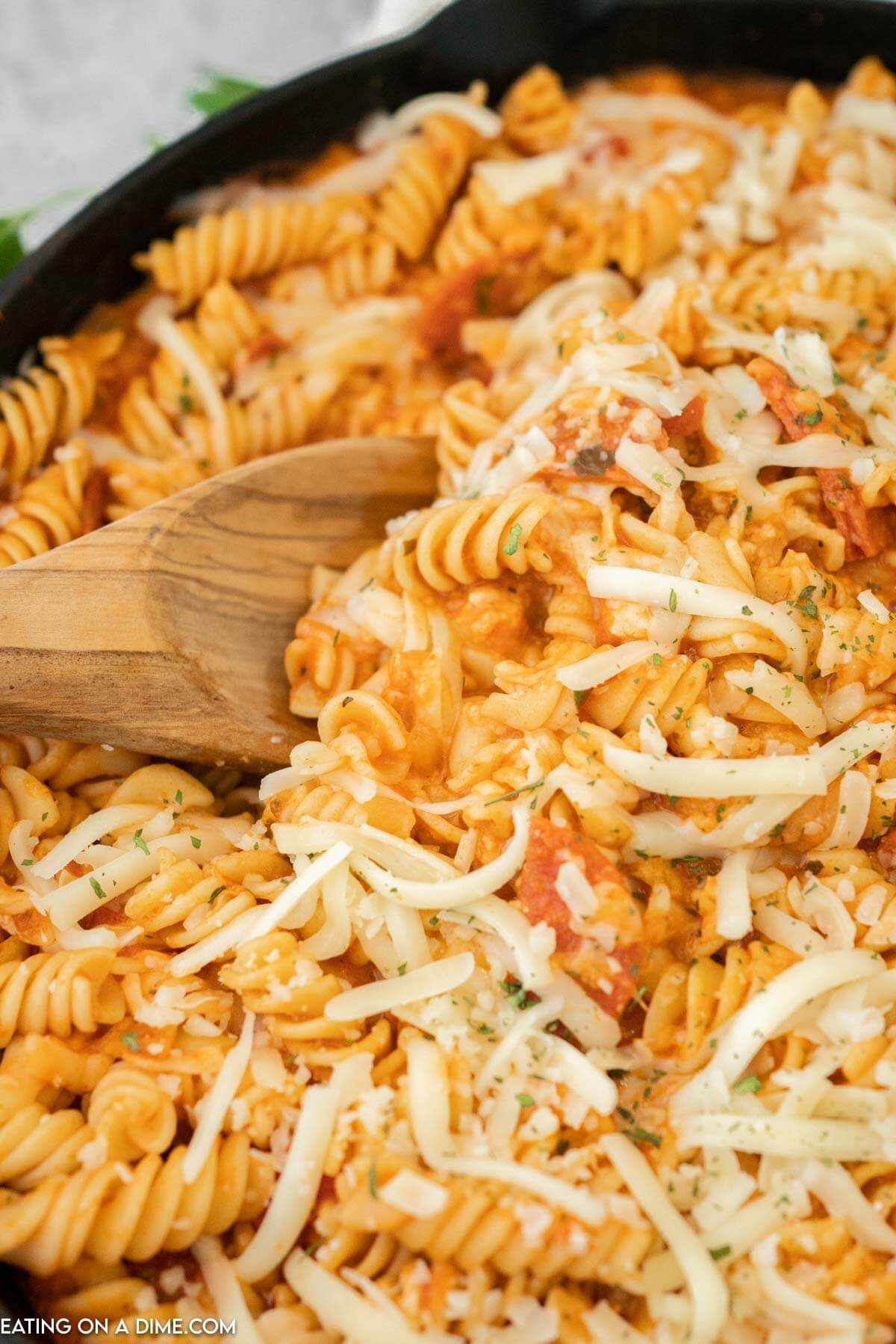 Pepperoni pasta being stirred with a wooden spoon