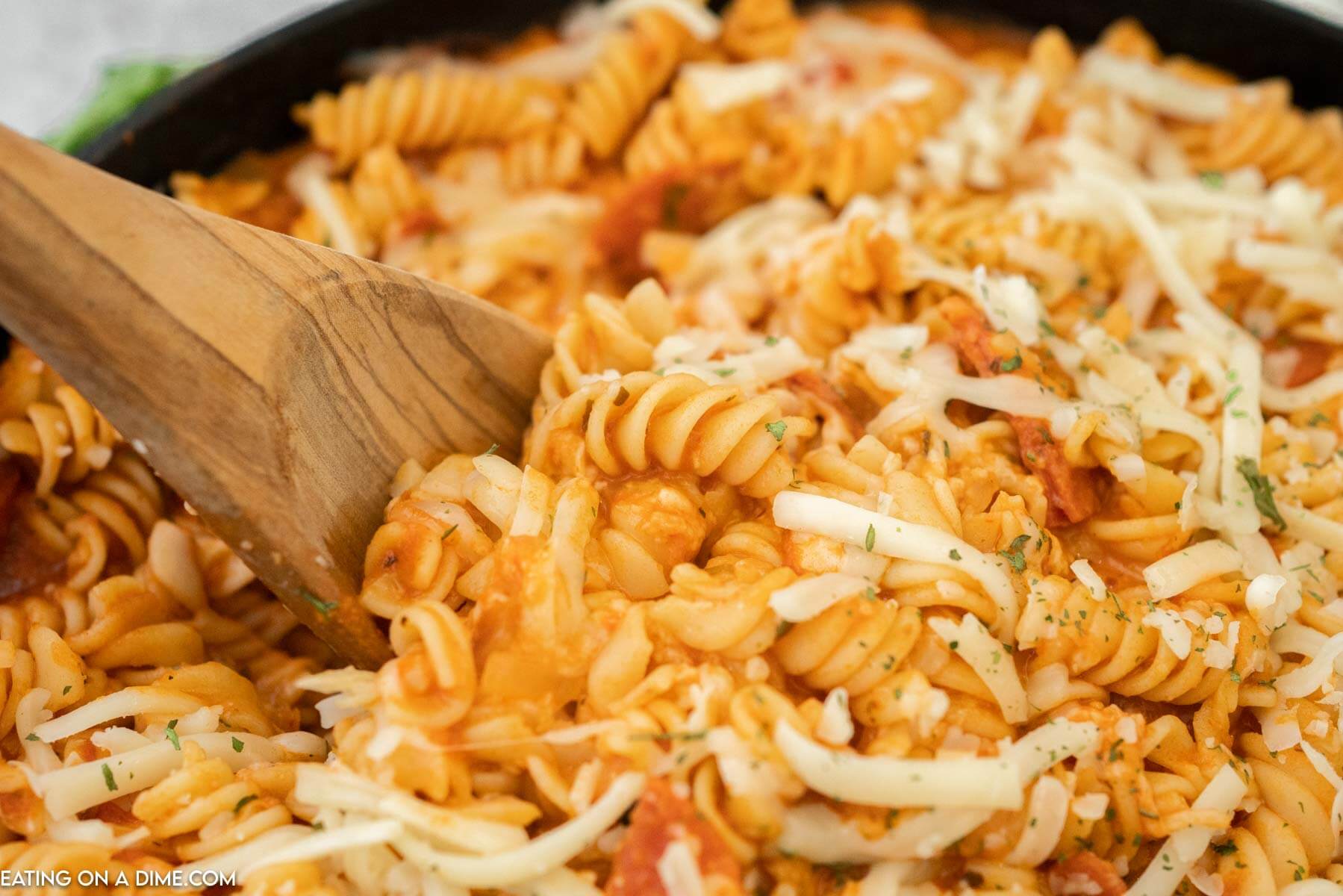 Pepperoni pasta being stirred with a wooden spoon