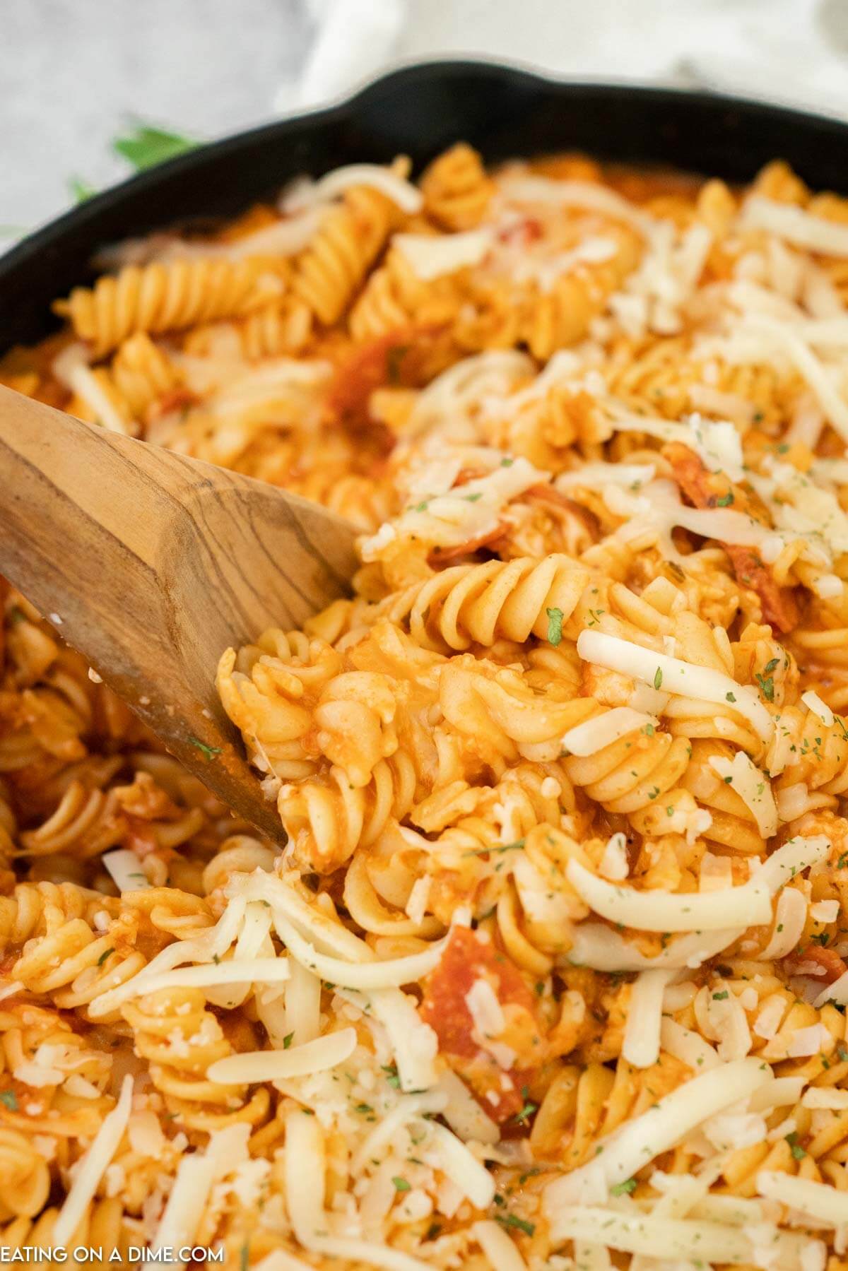 Pepperoni pasta being stirred with a wooden spoon