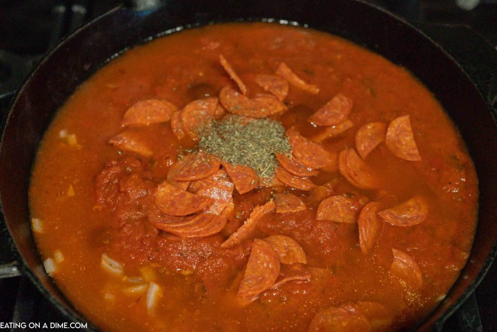 heating the marinara sauce, pepperoni, and seasoning in an iron skillet