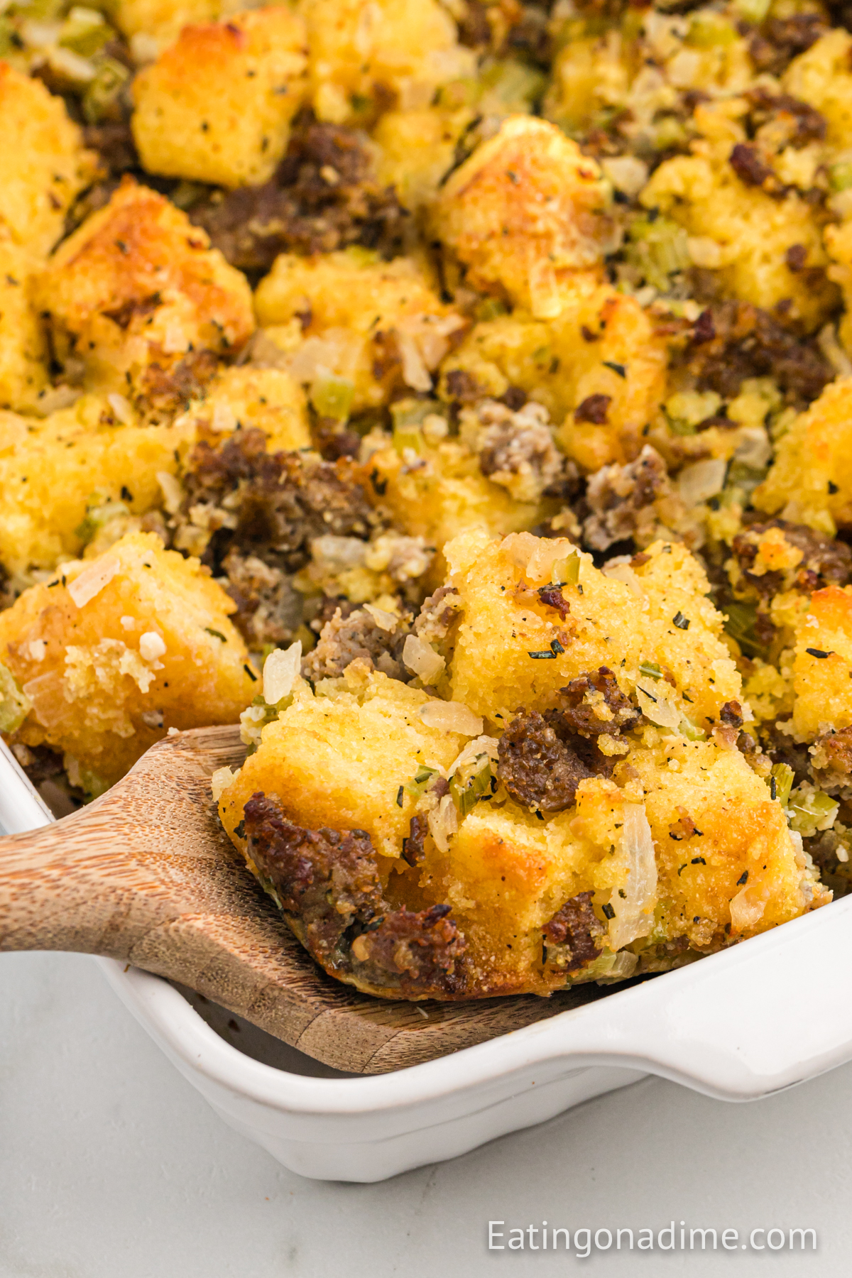 Cornbread Sausage Stuffing in a baking dish with a serving on a spatula