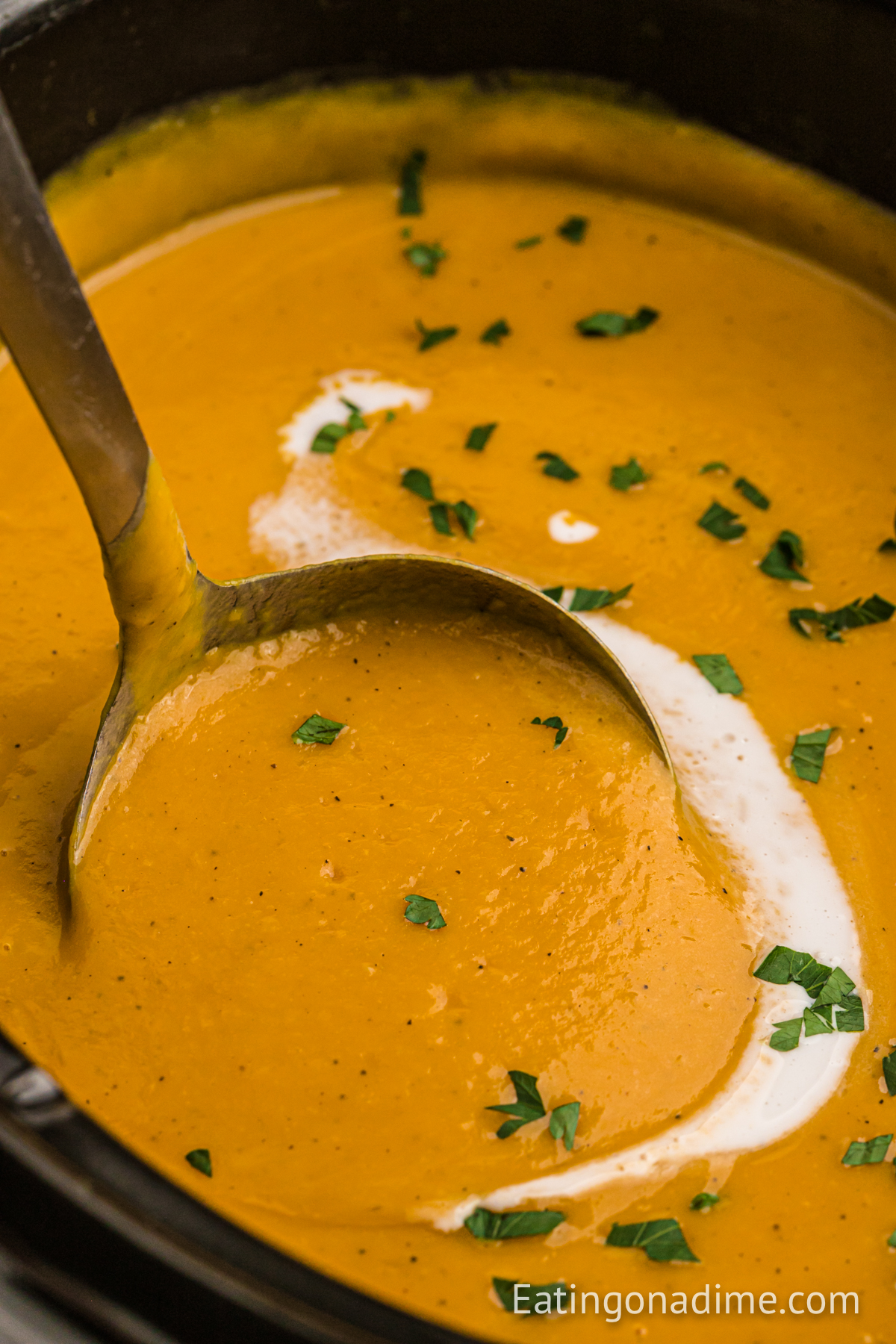 Sweet Potato Soup in the crock pot with a serving on a ladle 