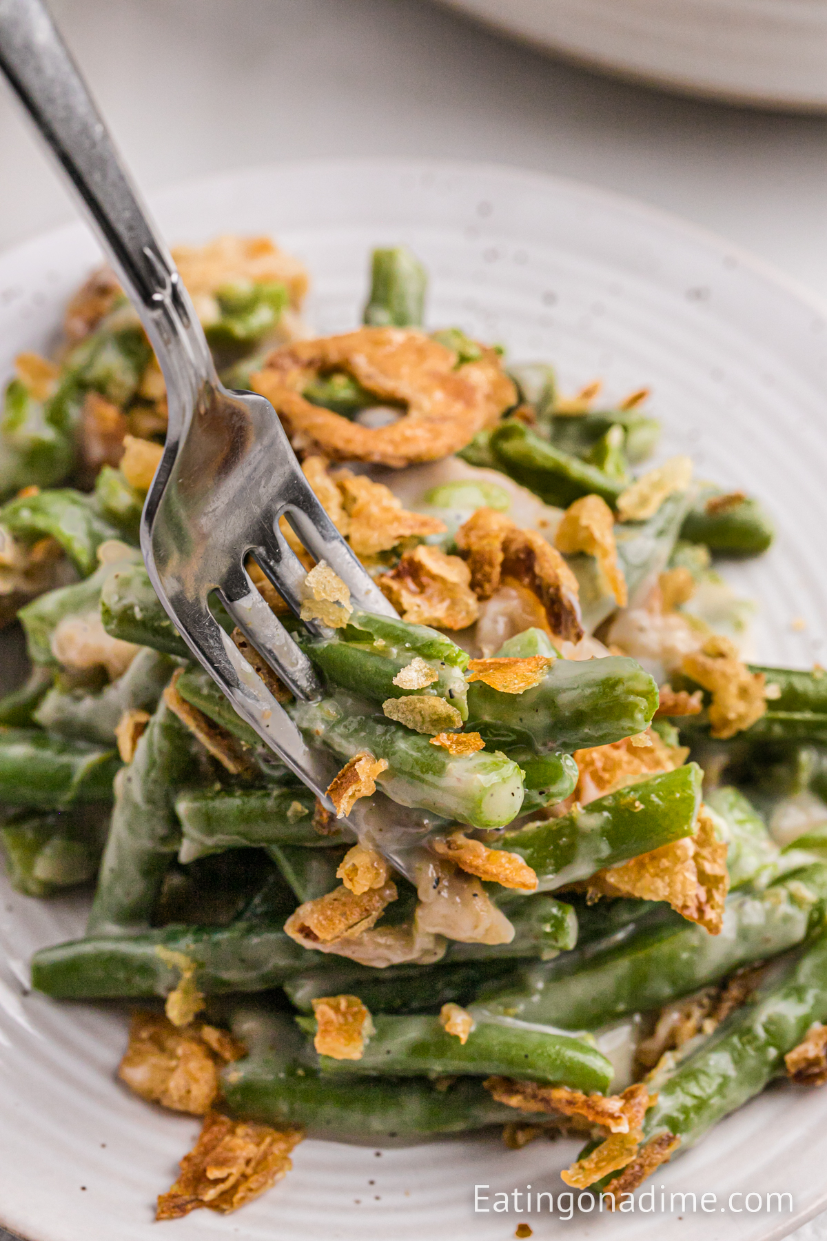 Green Bean Casserole on on white plate with a fork