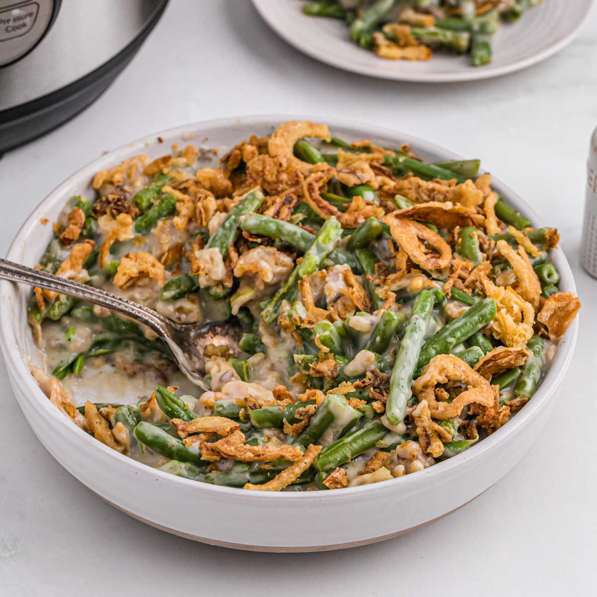 Green Bean Casserole in a white bowl with a spoon
