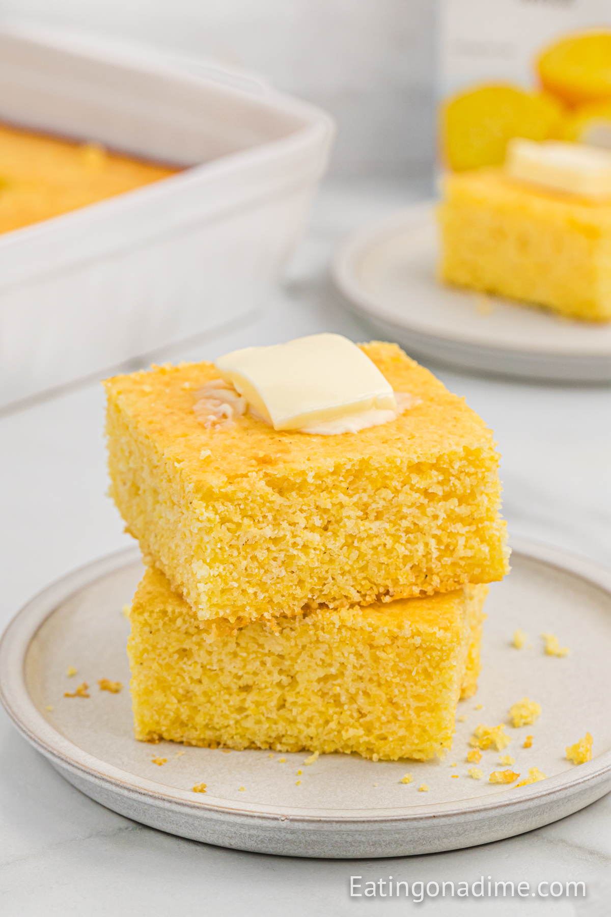 Two slices of cornbread on a plate butter on top and stacked