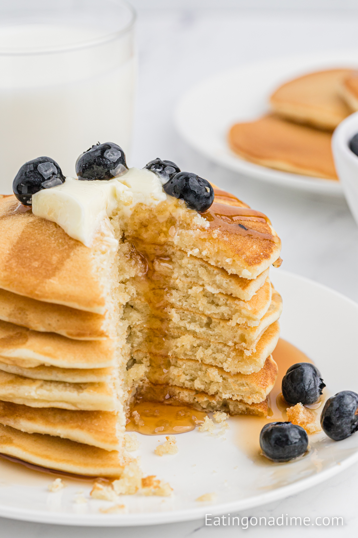 Sweet Cream Pancakes with butter, blueberries and syrup on the top with a serving missing