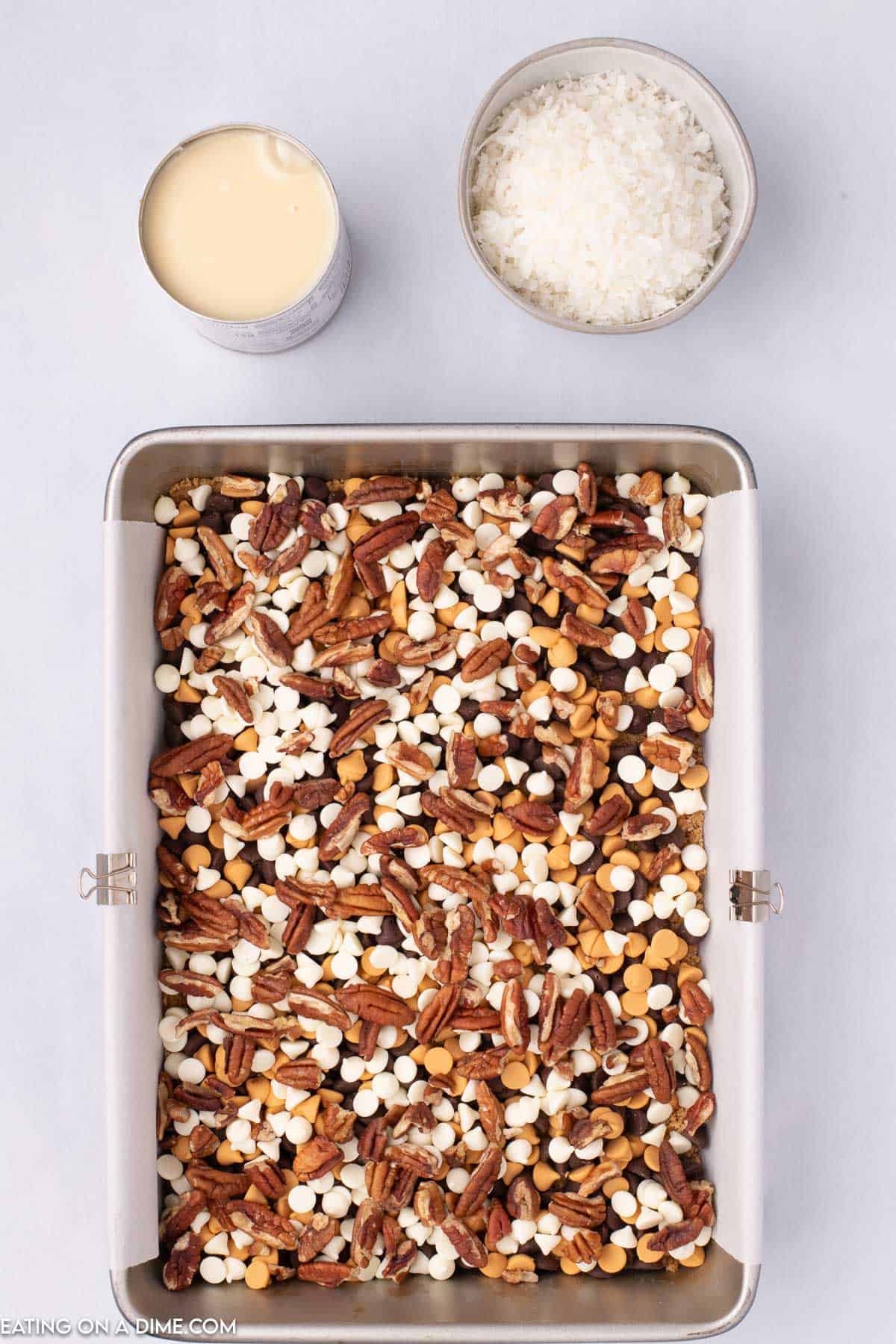 Pecans, chocolate chips topped on a graham cracker crust with a can of evaporated milk and shredded coconut
