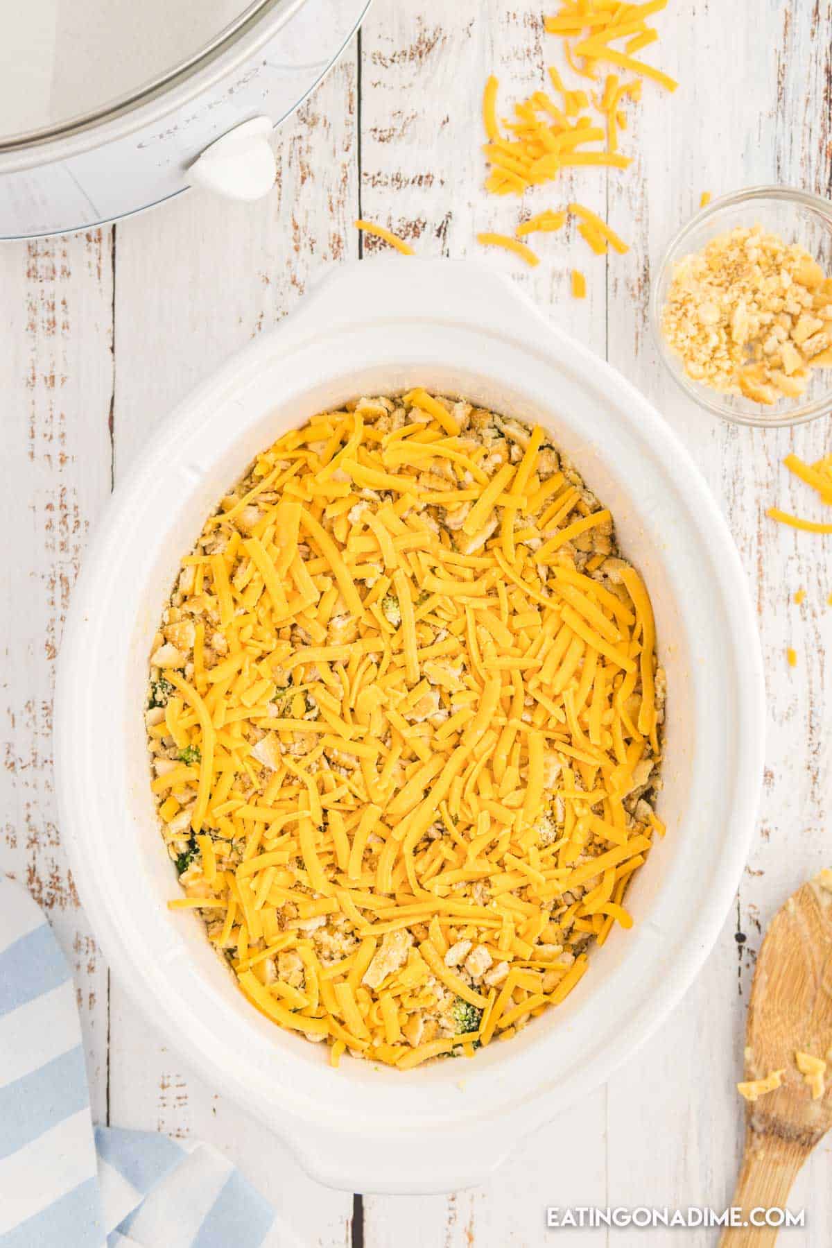 Topping the broccoli mixture with shredded cheese crushed crackers