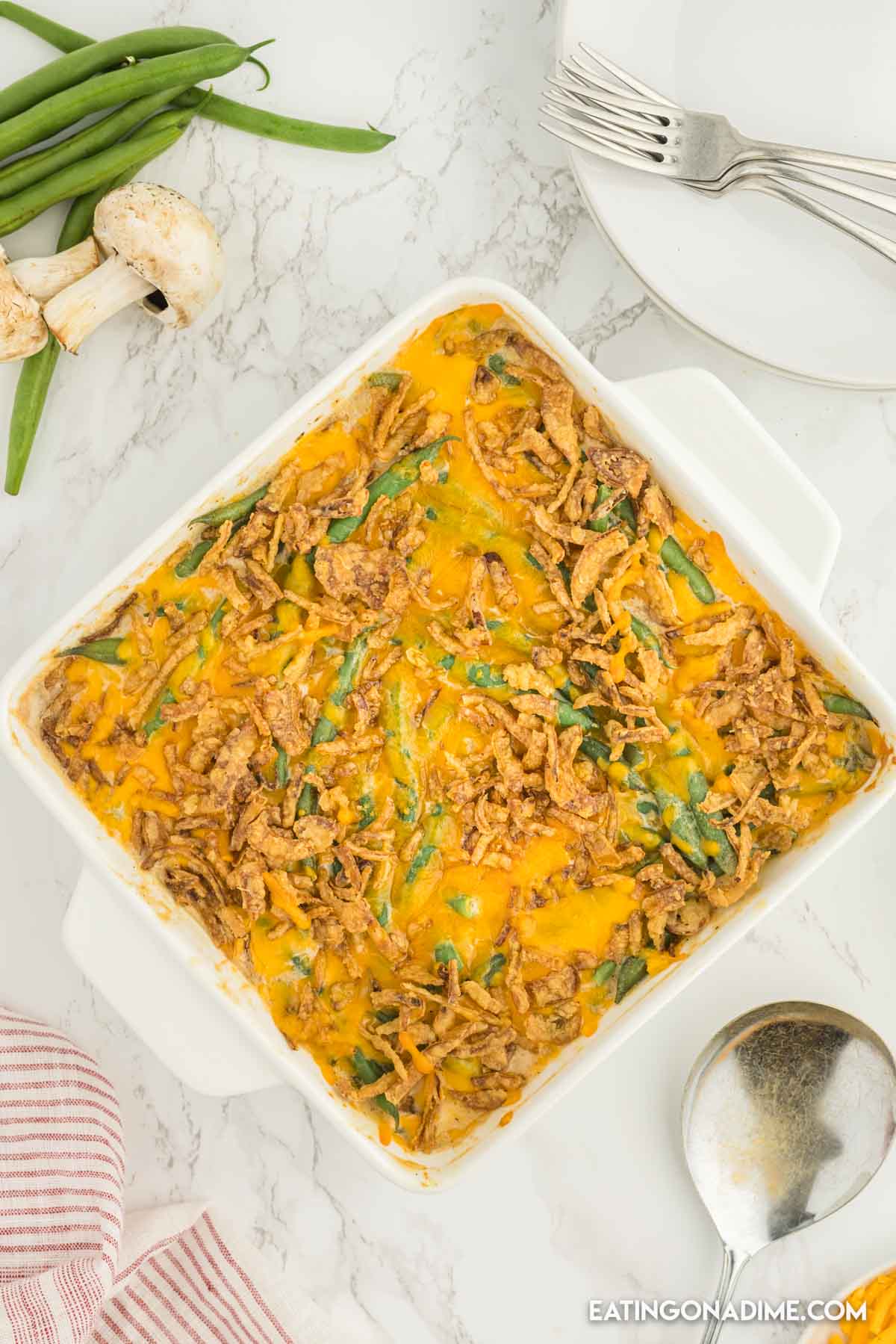 Cheesy green bean casserole in a baking dish with a spoon